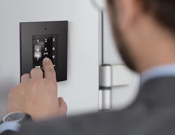 De 2N Access Unit 2.0 Touch keypad, Bluetooth en RFID met zwart frame ingebouwd bij een toegangsdeur
