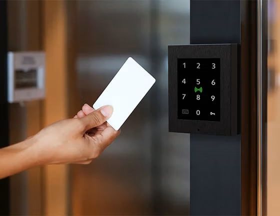 2N Access Unit 2.0 met Touch Keypad en RFID kaartlezer met zwarte opbouwbeugel en frame op een deurpost gemonteerd