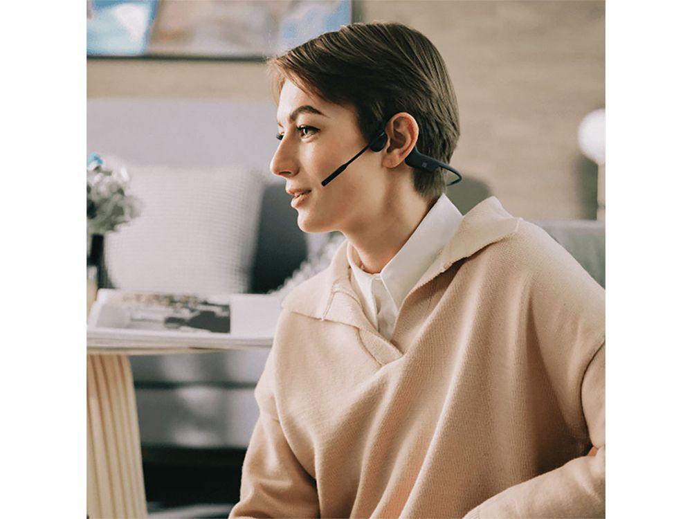 Een vrouw draagt de Shokz OpenComm2 UC stereo headset USB-A