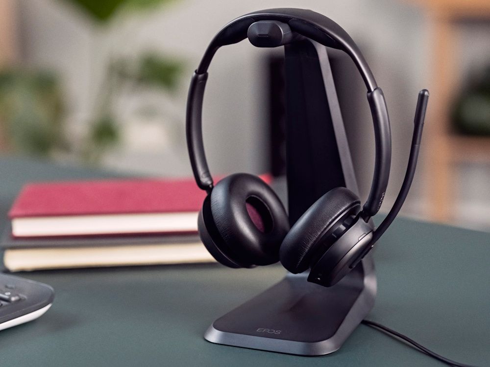 De EPOS IMPACT 1000 MS UC ANC WL dubbeloors Bluetooth headset op de laadstandaard op een bureau