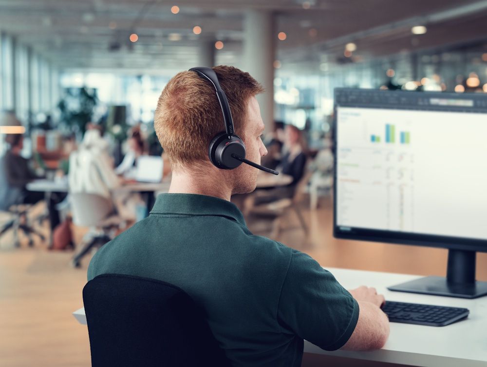Een man draagt de EPOS IMPACT 1000 MS UC ANC WL dubbeloors Bluetooth headset op kantoor