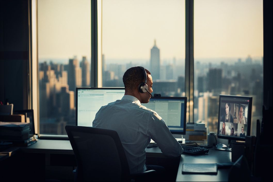Een man draagt de EPOS IMPACT 1000 MS UC ANC WL dubbeloors Bluetooth headset op zijn kantoor met uitzicht over de stad