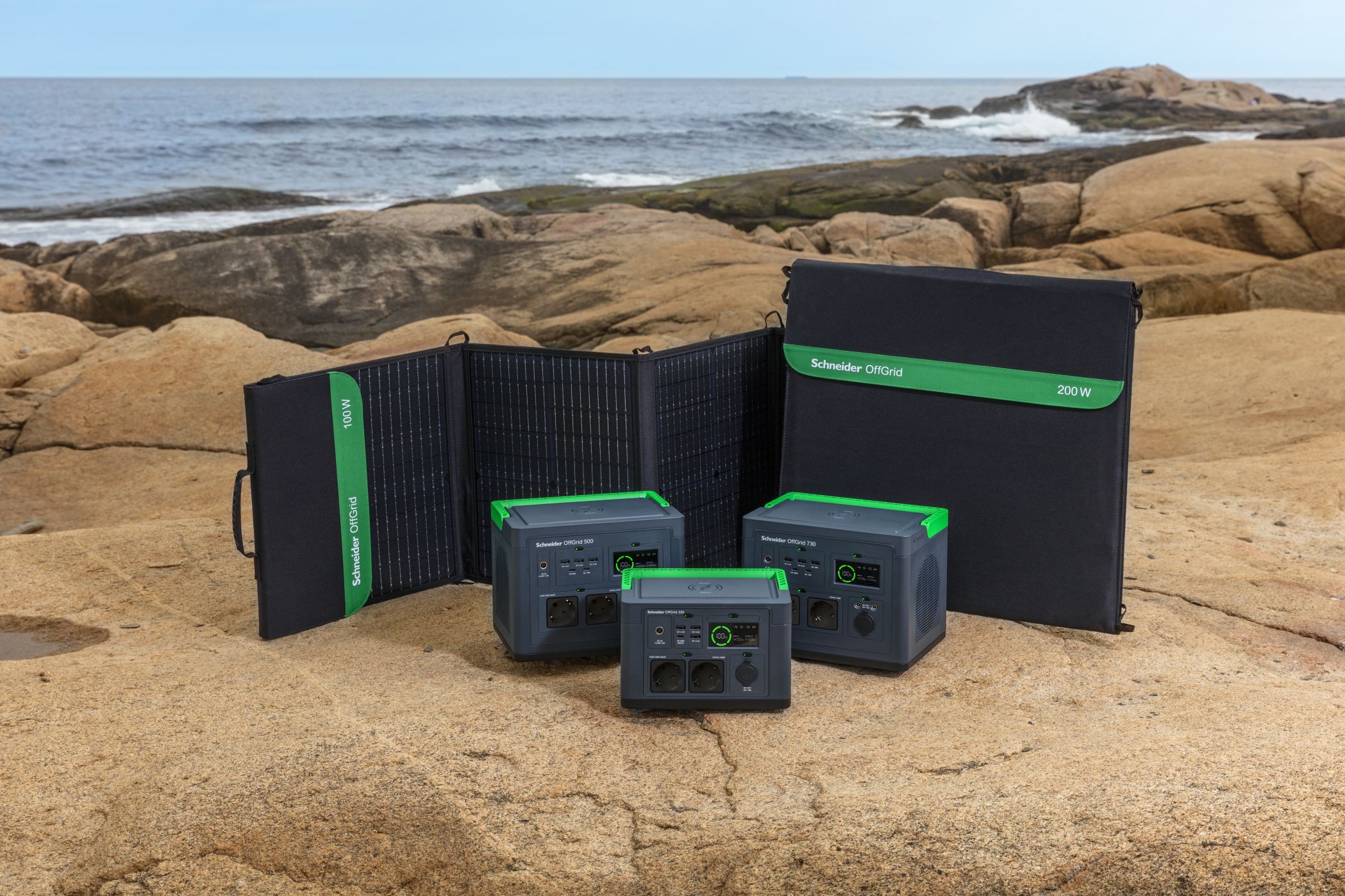 Het Schneider OffGrid PSP100 OffGrid draagbare zonnepaneel 100W voor draagbare Schneider OffGrid oplaadstations die ervoor staan op de rots aan zee