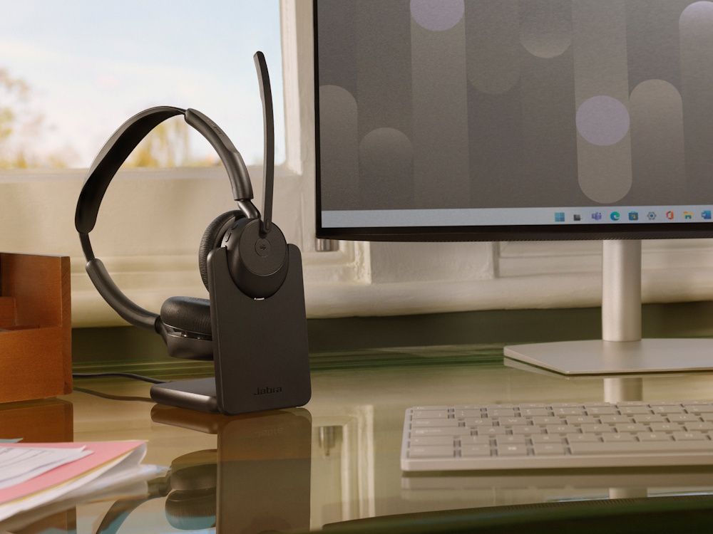 De Jabra Evolve3 45 MS Teams stereo Bluetooth headset met laadstation op een bureau op een moderne werkplek