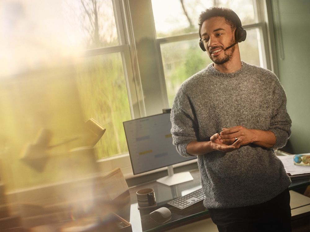 Een man draagt de Jabra Evolve3 45 UC stereo Bluetooth headset in zijn thuiskantoor