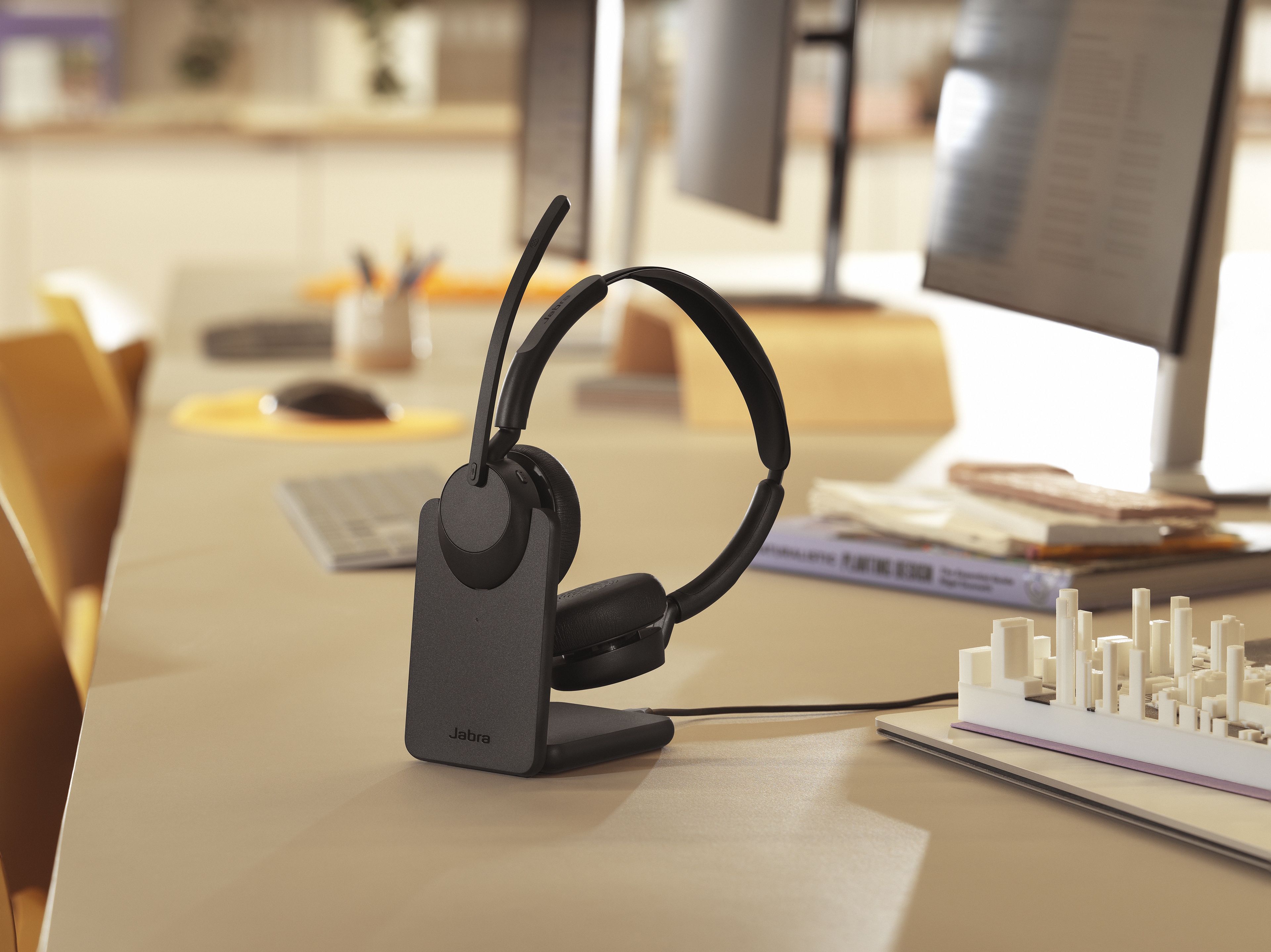 De Jabra Evolve3 45 UC stereo Bluetooth headset met oplader op een bureau in een kantoor