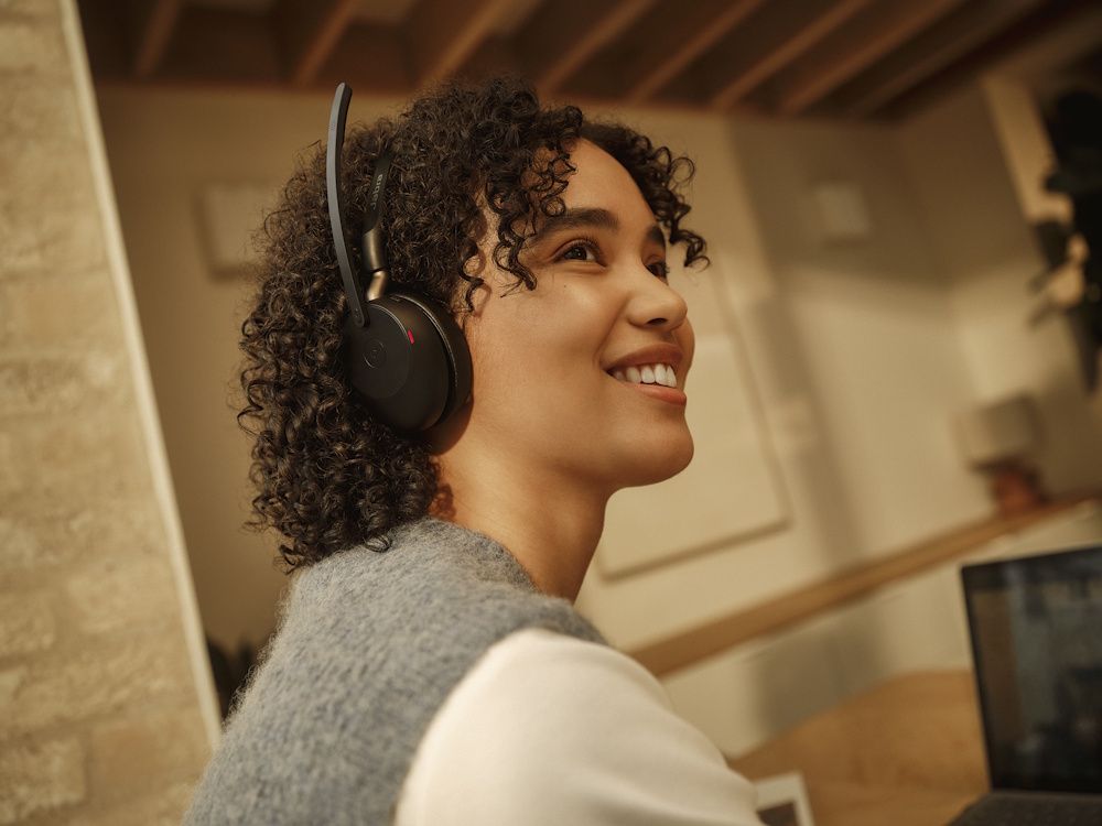 Een vrouw draagt de Jabra Evolve3 65 MS mono Bluetooth headset in een druk kantoor