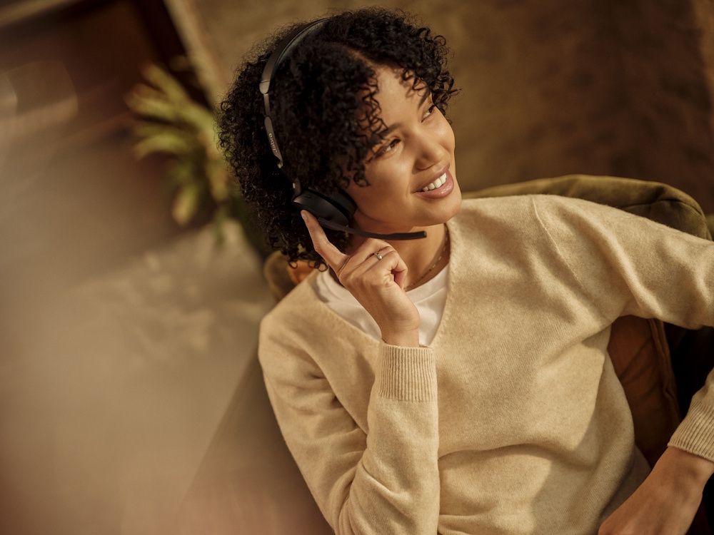 Een vrouw draagt een Jabra Evolve3 65 MS Teams stereo Bluetooth headset in een druk kantoor