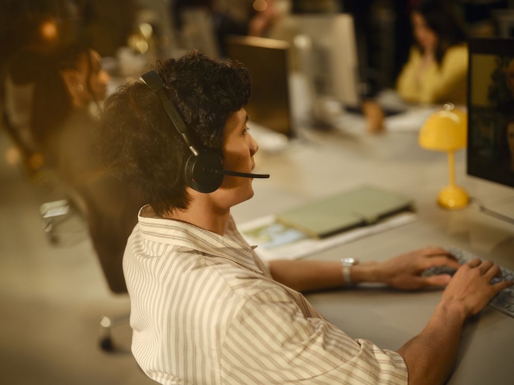 Een man draagt de Jabra Evolve3 65 MS Teams stereo Bluetooth headset in een druk kantoor