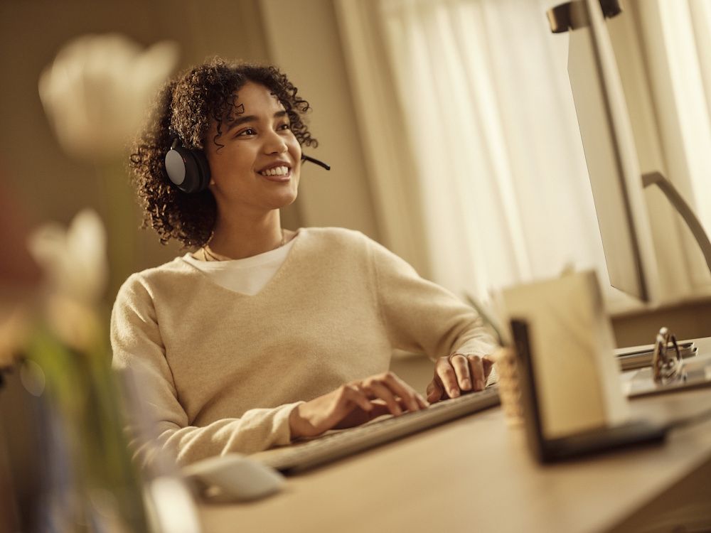 Een vrouw draagt een Jabra Evolve3 65 UC stereo Bluetooth headset in een druk kantoor