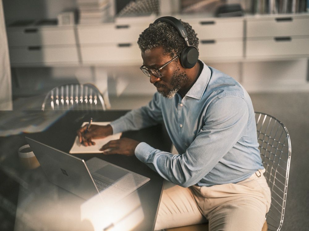 Een hybride werker draagt de draadloze Jabra Evolve3 75 MS Bluetooth headset achter zijn laptop op een flexibele werkplek
