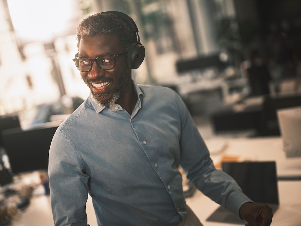 Een zakelijke professional draagt de draadloze Jabra Evolve3 75 MS Bluetooth headset op kantoor op zijn werkplek