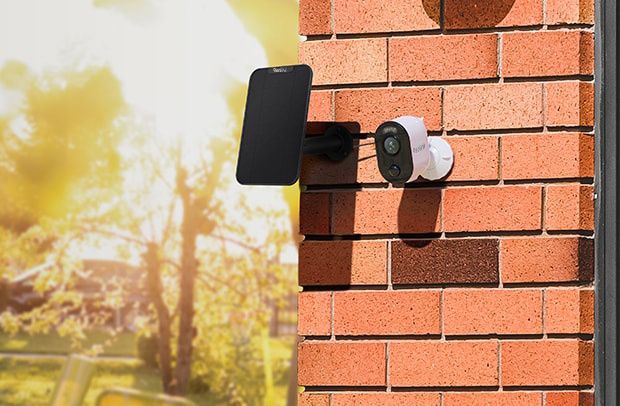 Het Reolink Solar Panel 3 Black 12W zonnepaneel voor Reolink accu camera's gemonteerd aan een buitenmuur naar een camera