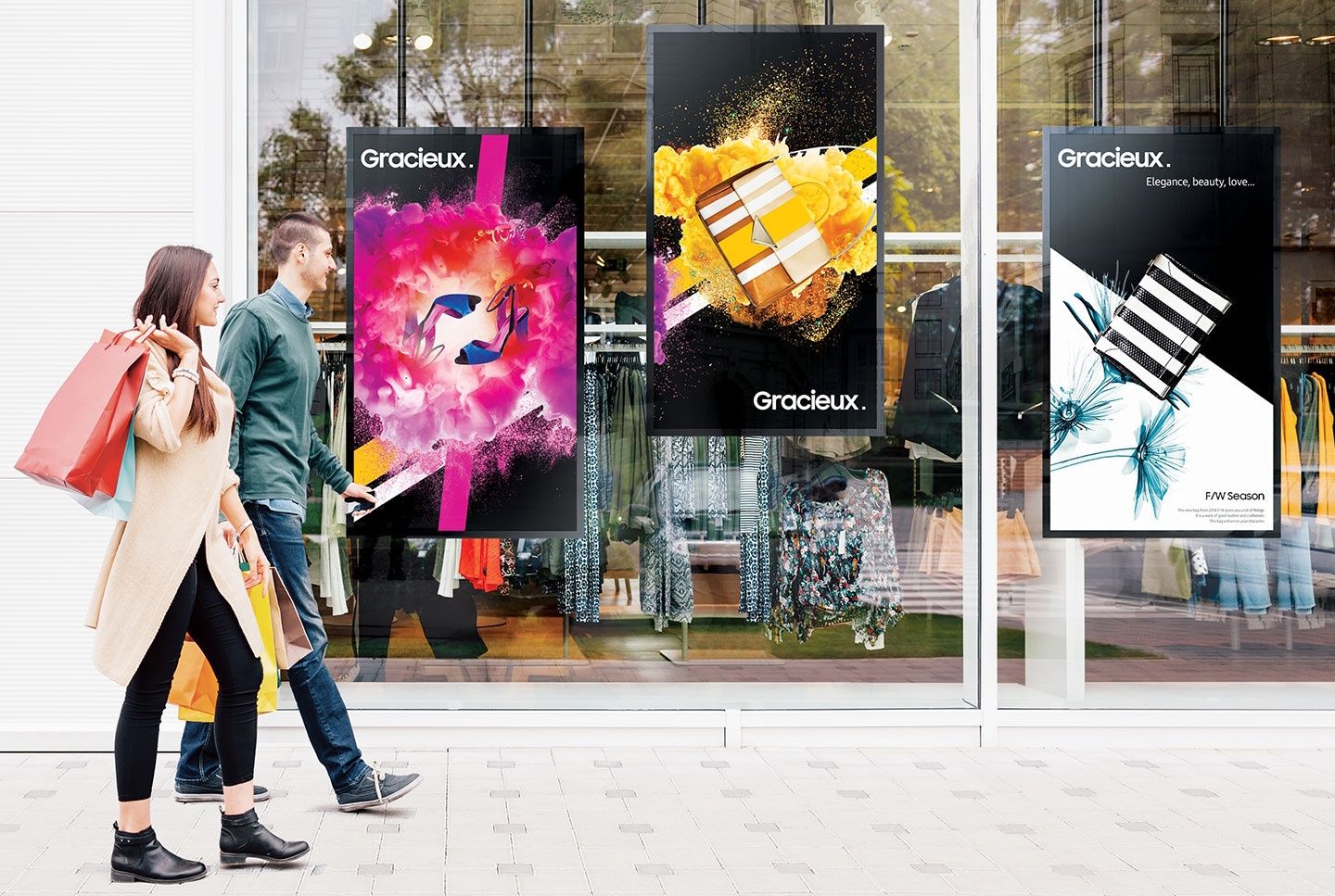 Drie Samsung OM55N-S Full HD High Brightness Etalage Schermen in een etalage van een retailer of kledingwinkel