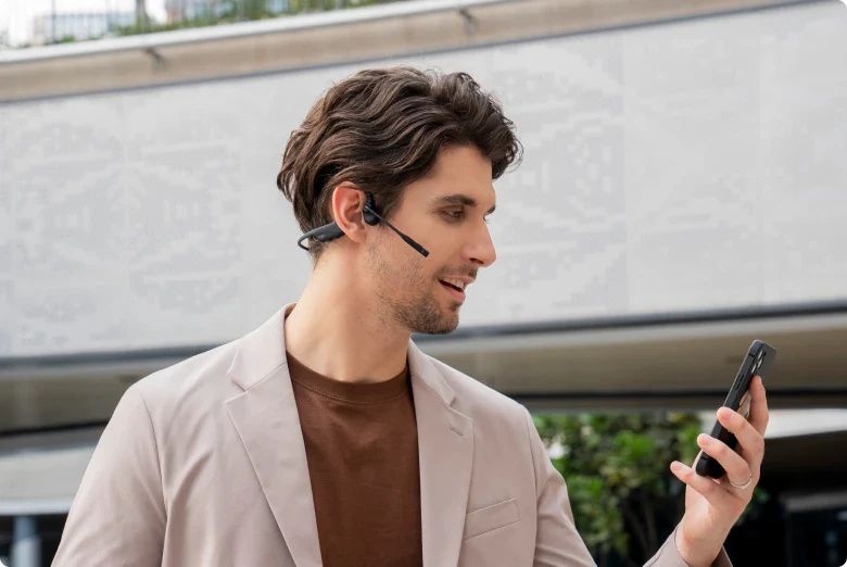 Man onderweg gebruikt de dubbeloors Shokz OpenComm2 bone conduction open-ear headset