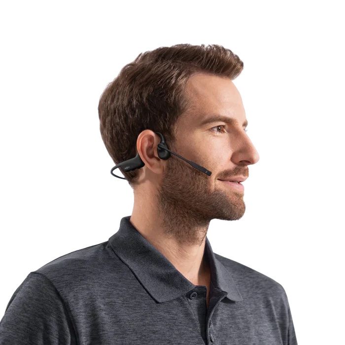 Een man draagt de dubbeloors Shokz OpenComm2 bone conduction open-ear headset