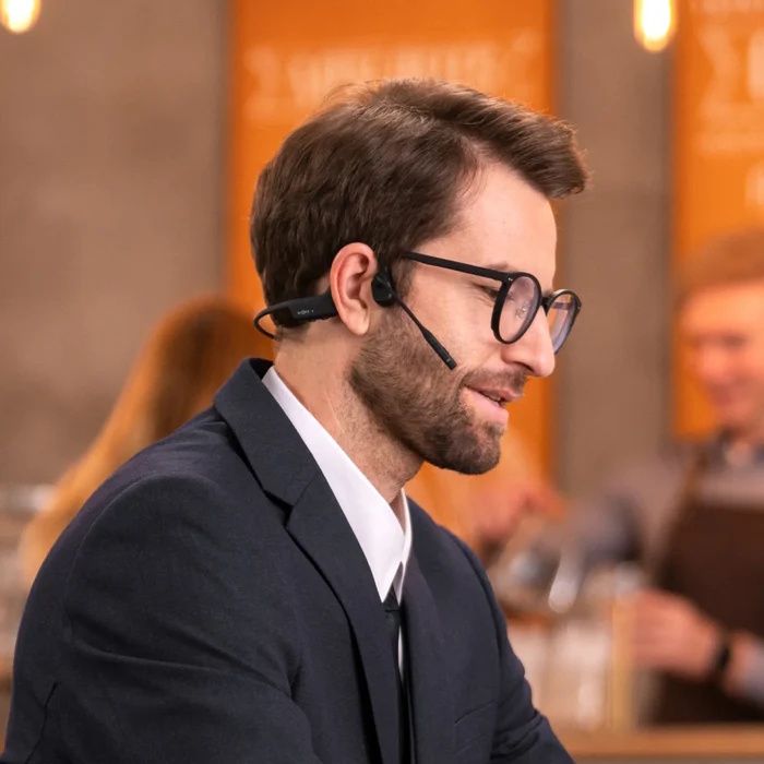 Man draagt de dubbeloors Shokz OpenComm2 bone conduction open-ear headset in een horecagelegenheid