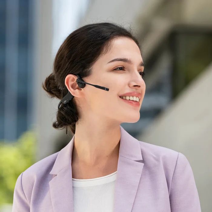 Vrouw draagt buiten en onderweg de dubbeloors Shokz OpenComm2 bone conduction open-ear headset