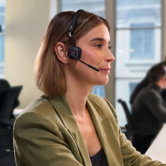 Een vrouw draagt op kantoor de zakelijke Shokz OpenMeet UC bone conduction en air conduction open-ear headset