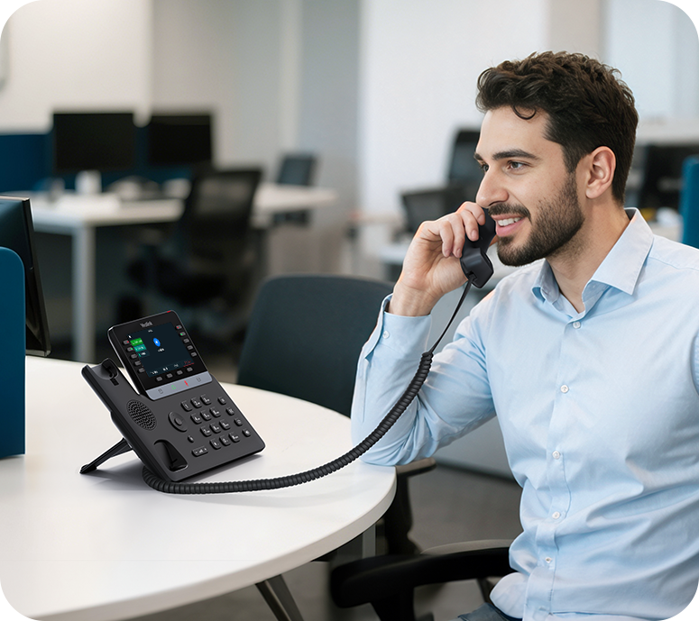 Een man belt via de Yealink SIP-T74W VoIP telefoon die op zijn bureau staat in een kantoorruimte