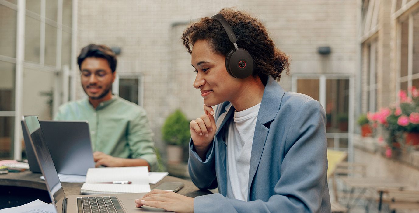 Een vrouw draagt de Yealink WH68 Workstation UC headset met DECT en Bluetooth op een flexibele werkplek