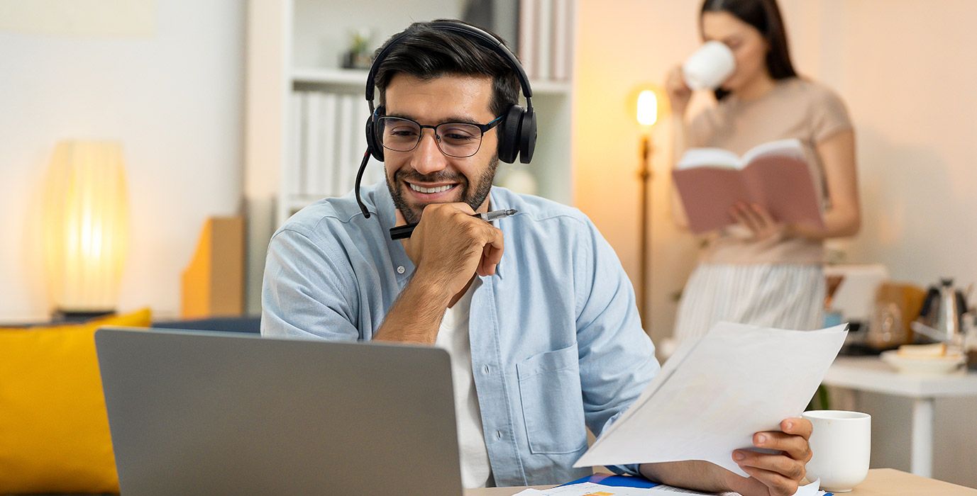 Een man draagt een Yealink WH68 Workstation UC headset met DECT en Bluetooth op zijn thuiswerkplek