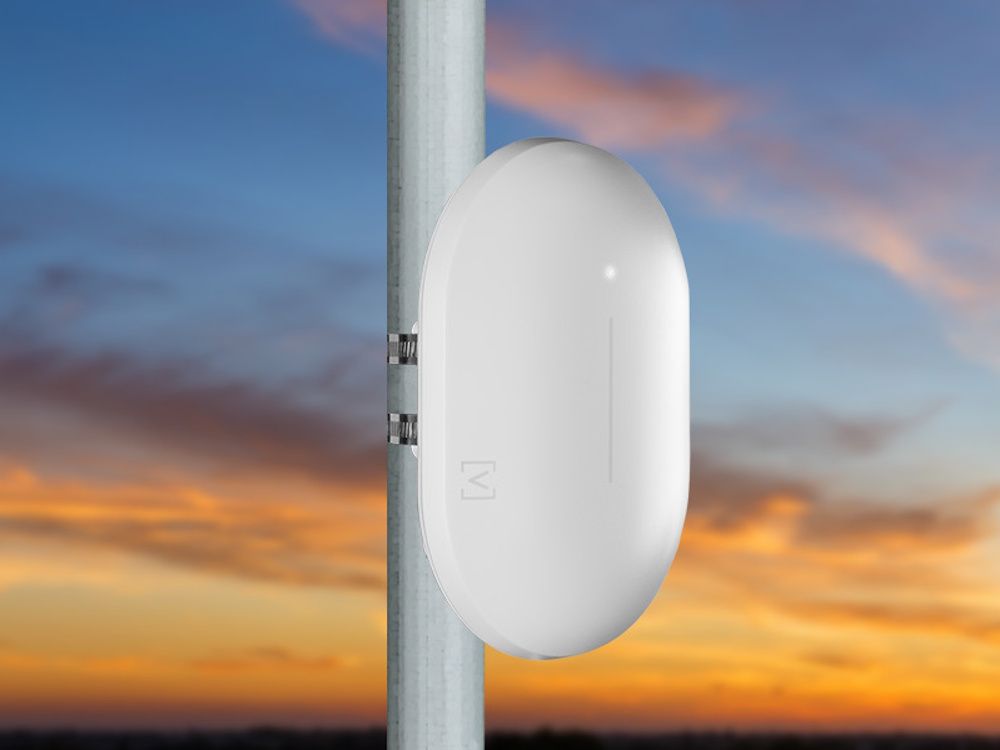 Het Alta Labs AP6-Pro Outdoor WiFi 6 Cloud 4x4 access point buiten aan een paal of mast gemonteerd met ondergaande zon op de achtergrond