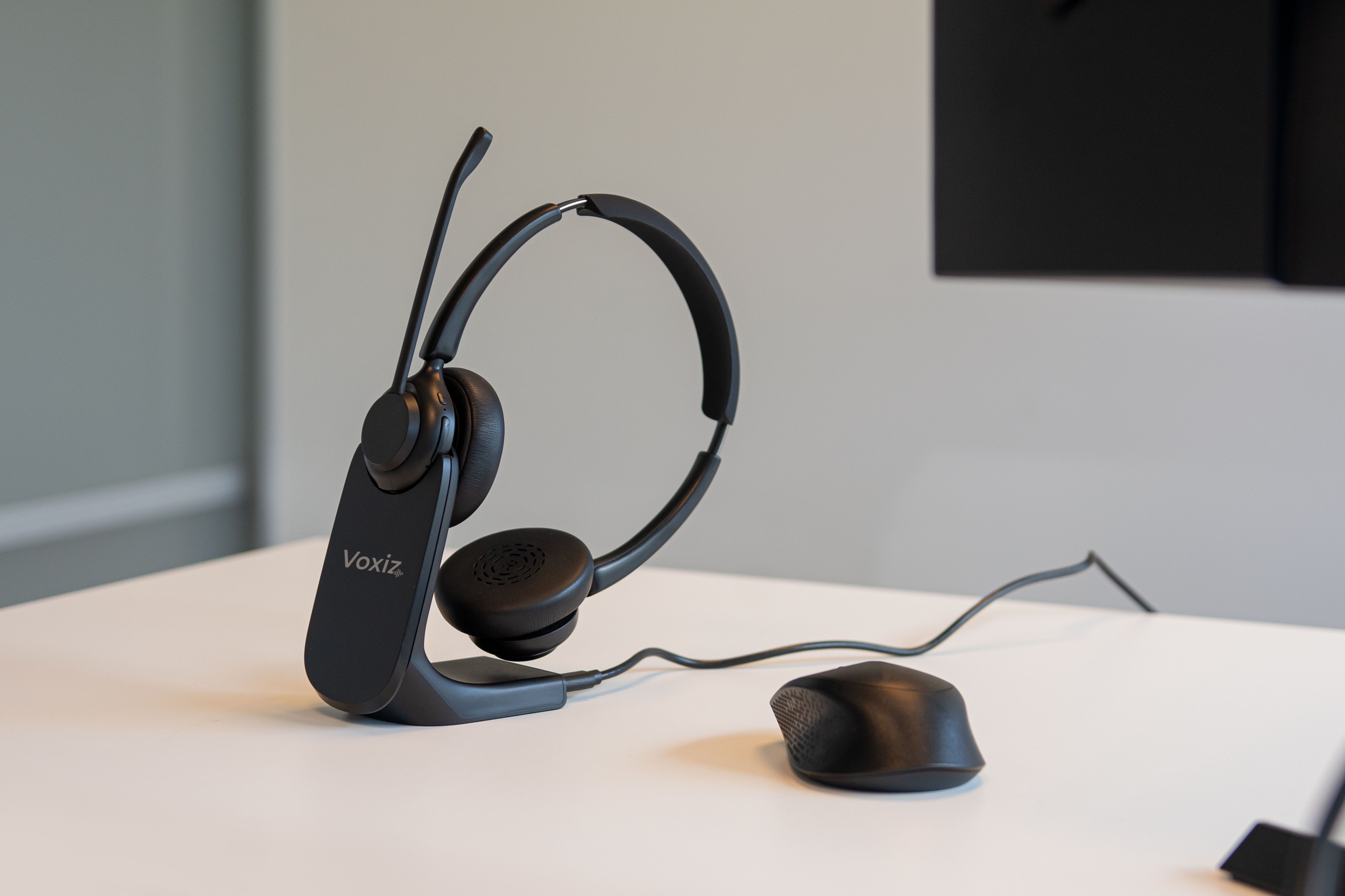 De Voxiz Wireless dubbeloors Bluetooth office headset met microfoon op een bureau in een kantoor