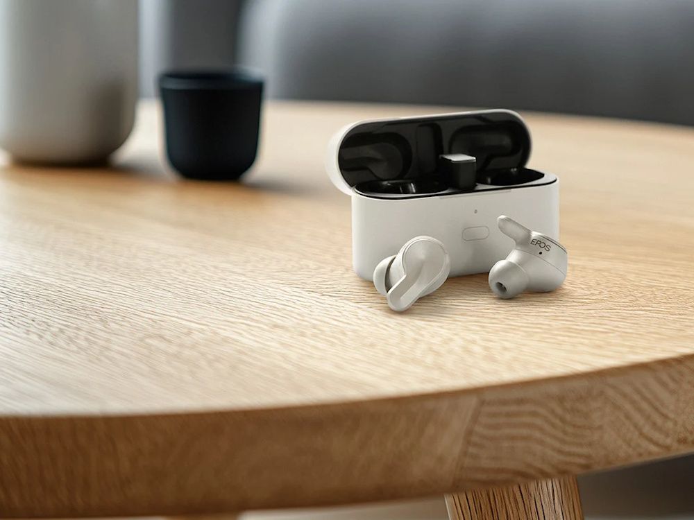 De EPOS Adapt E1 Nordic White draadloze Bluetooth oortjes voor professionals voor de oplaadcase of opbergcase op een ronde houten tafel