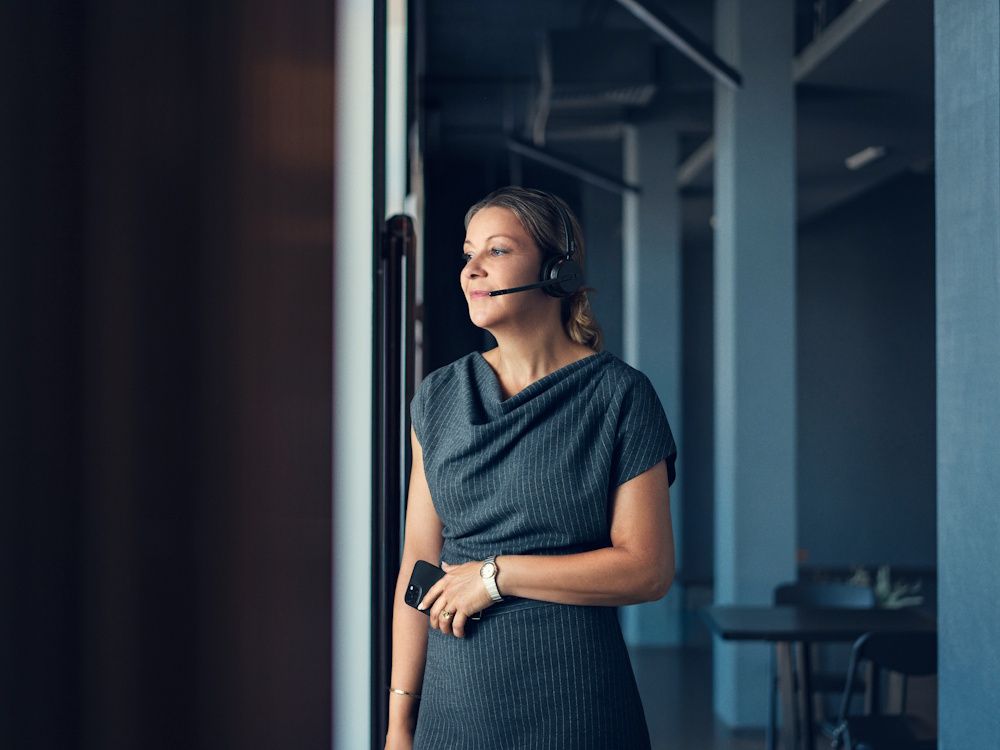 De EPOS IMPACT 500 draadloze Bluetooth headset in gebruik door een vrouw die in een kantoorruimte staat