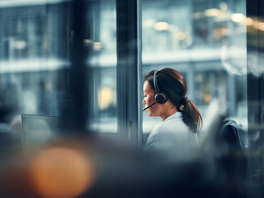 De EPOS IMPACT 500 draadloze Bluetooth headset in gebruik door een vrouw die achter de laptop aan het werk is