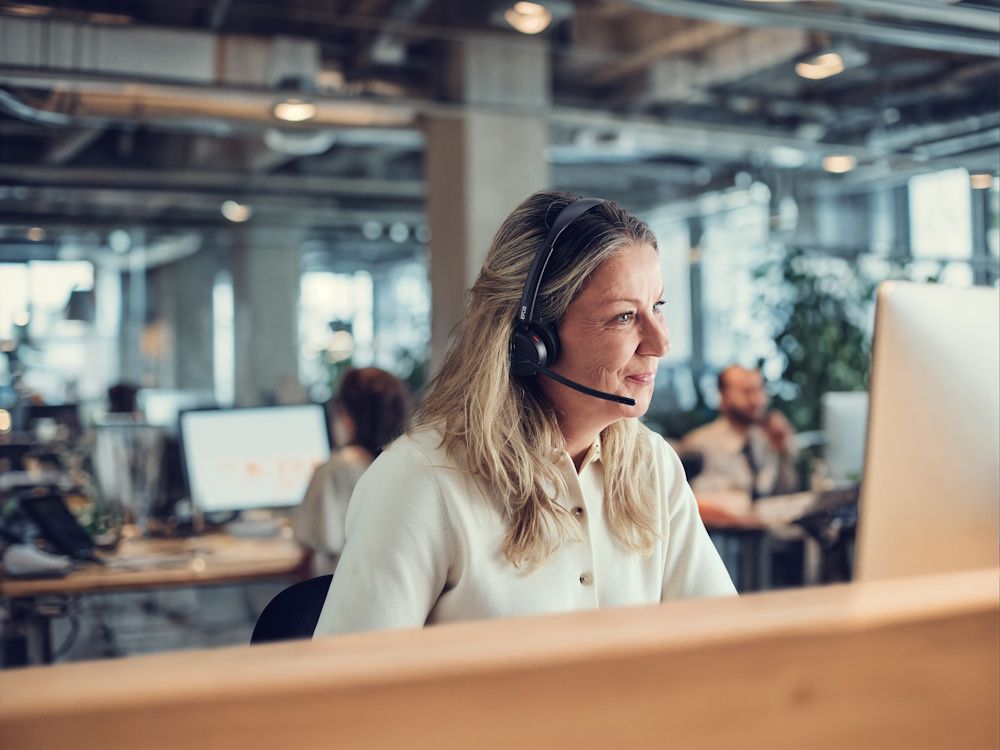 De EPOS IMPACT 500 draadloze Bluetooth headset in gebruik in een open office kantoor door een vrouw die belt