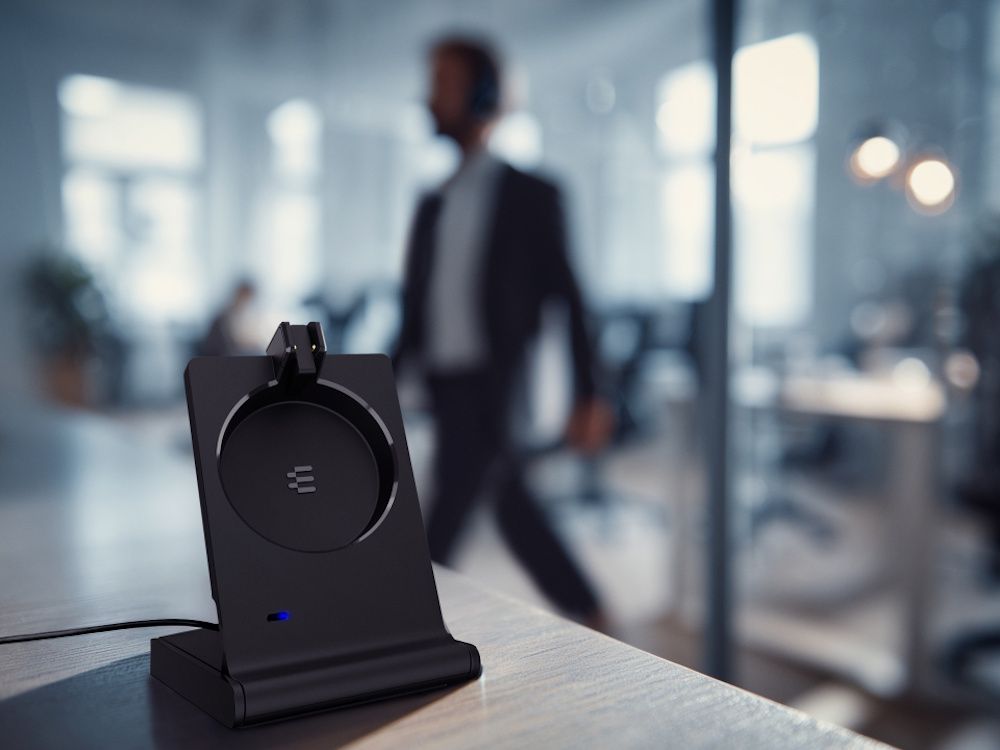 Het laadstation vann de EPOS IMPACT 5000 Go MS Mono 3-in-1 flexibele DECT headset op een bureau in een kantoor
