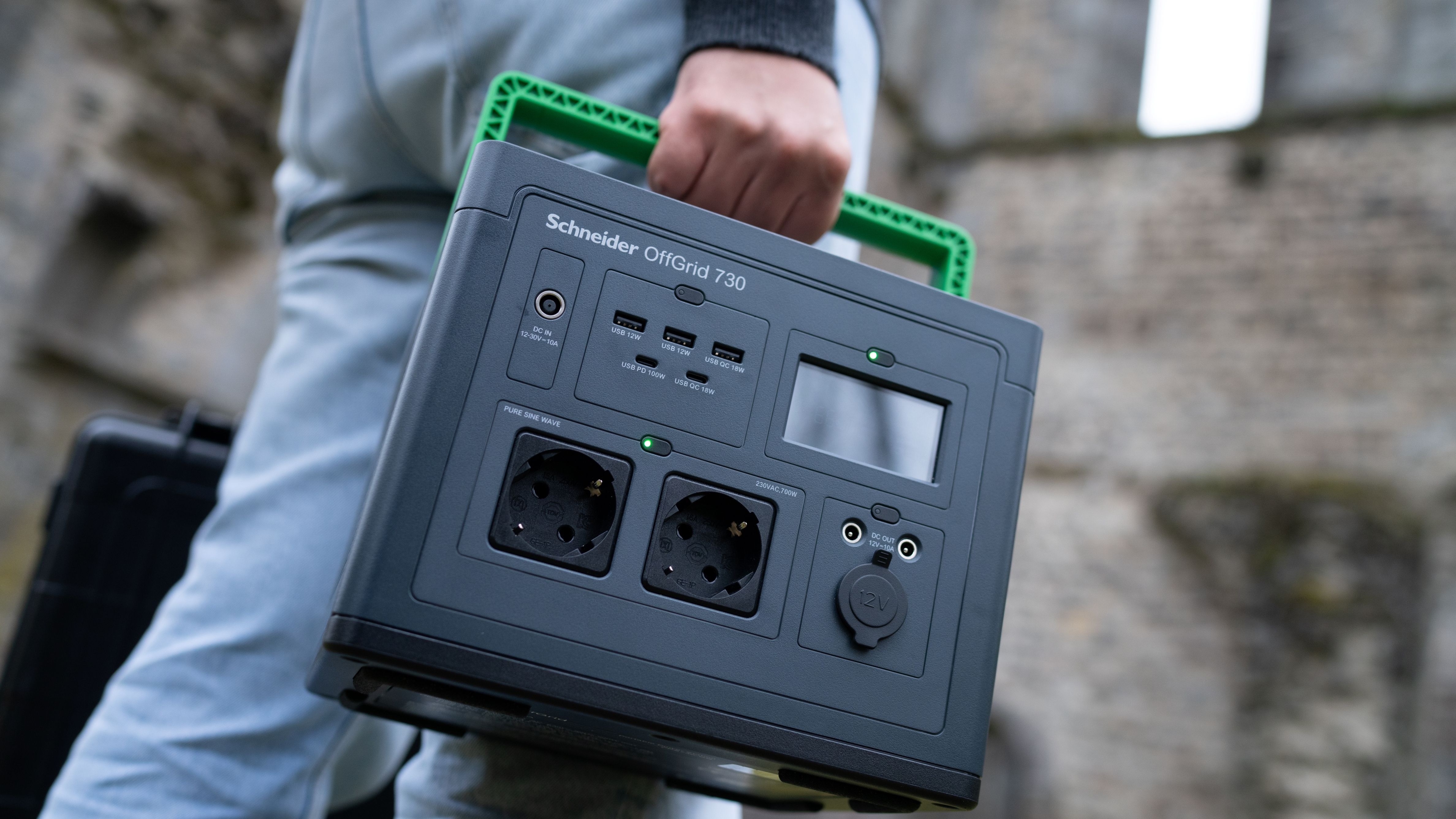 Een persoon houdt het APC PPS730-GR draagbare oplaadstation vast