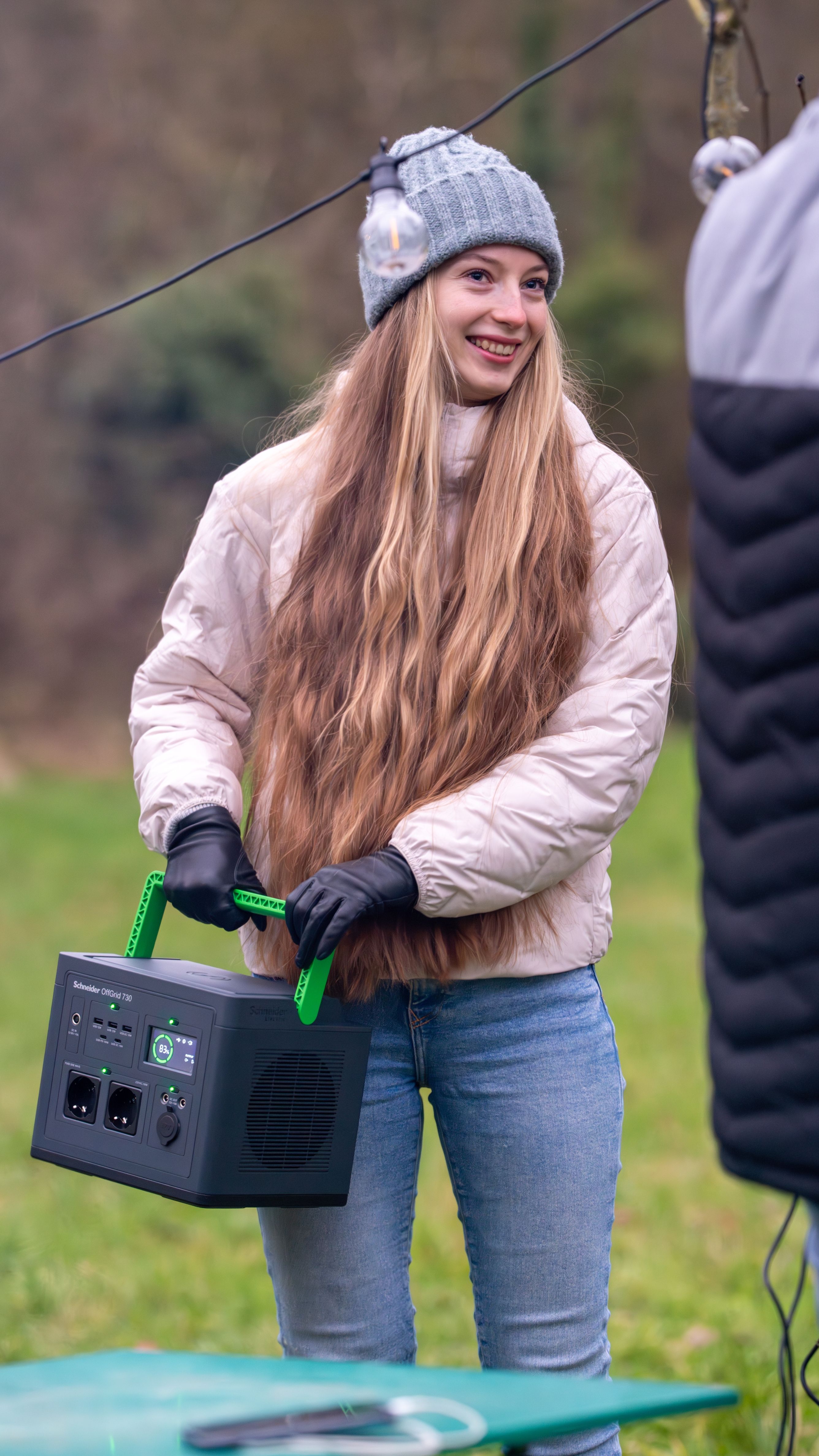 Een persoon houdt het APC PPS730-GR draagbare oplaadstation vast buiten op een camping