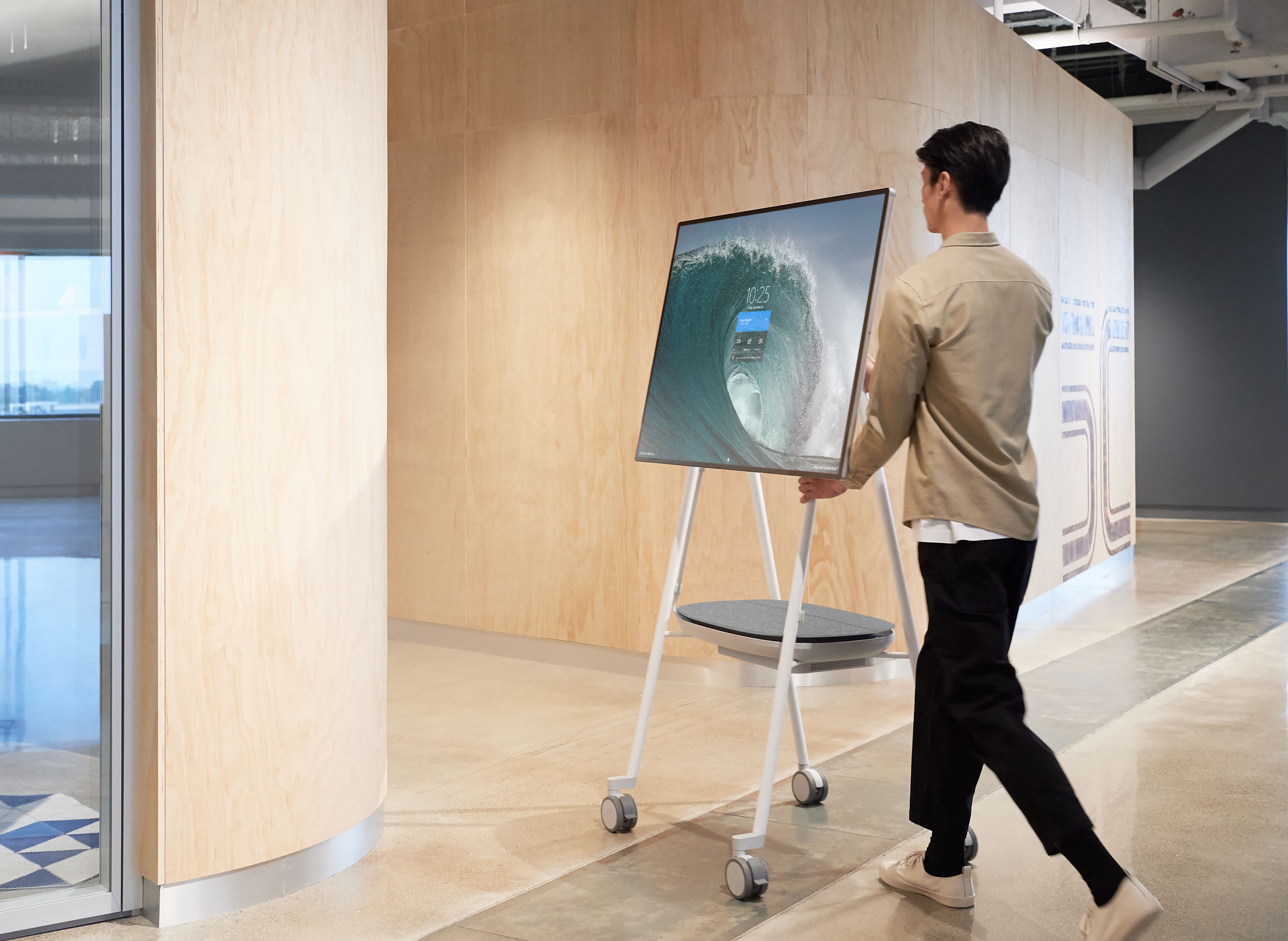 Sfeerfoto van de APC CSH2 Smart-UPS mobiele accu die inclusief Microsoft Surface Hub 2S of 3 door een gang wordt gereden