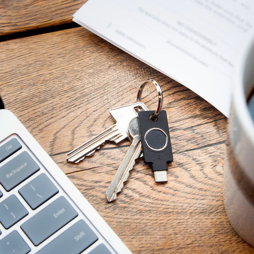 Yubico YubiKey Bio USB-C security key aan een sleutelbos naast een laptop