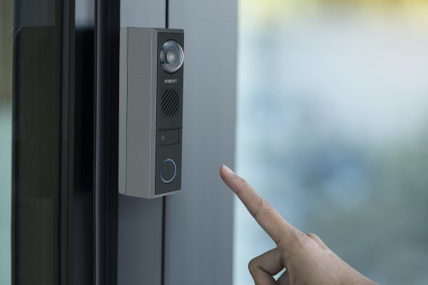 De Hanwha TID-600R 2MP Video Intercom aan een deurpost geïnstalleerd en iemand wil op de bel drukken