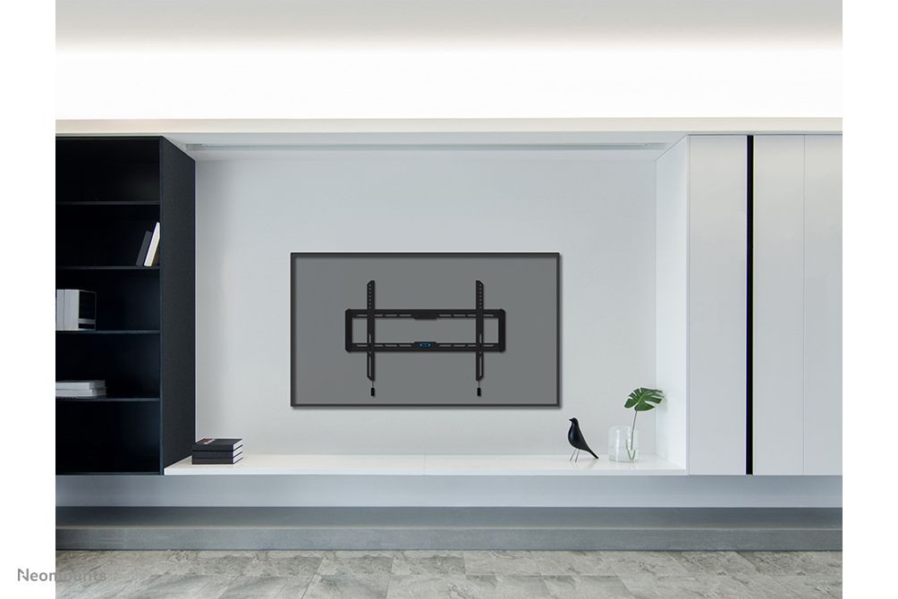 De Neomounts WL30-550BL16 muurbeugel voor displays van 42" tot 86" gemonteerd aan de muur in een strakke omgeving