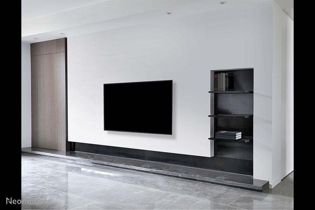 De Neomounts WL30-550BL12 muurbeugel voor displays van 24'' tot 65'' draagt een scherm en hangt aan de muur