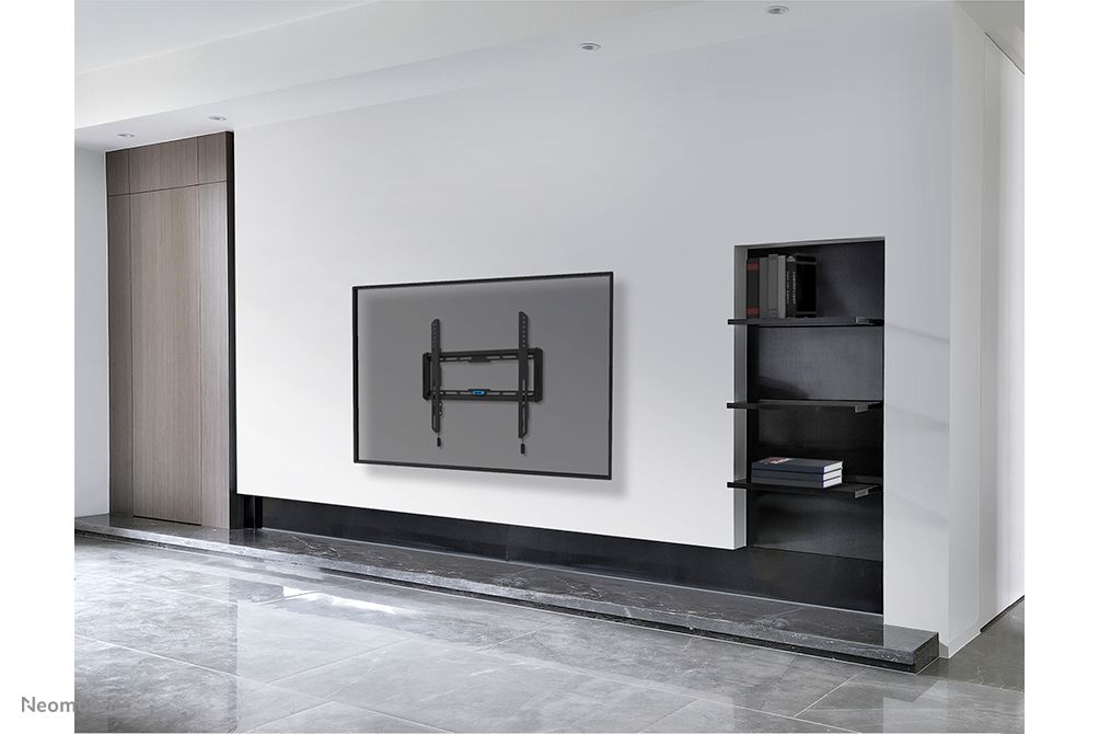 De Neomounts WL30-550BL14 muurbeugel voor displays van 32'' tot 75'' aan de wand gemonteerd in een zakelijke omgeving