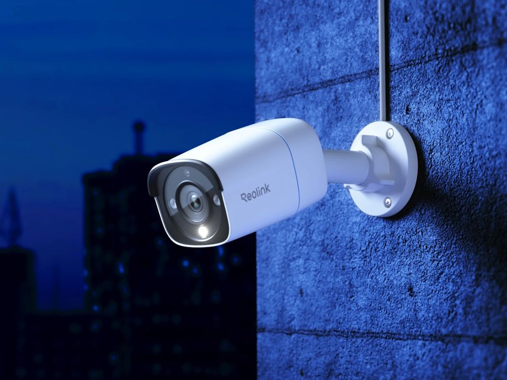 Sfeerfoto van de Reolink Pro RP-PCB8M-W slimme  4K 8MP outdoor PoE camera aan een buitenmuur gemonteerd in het donker