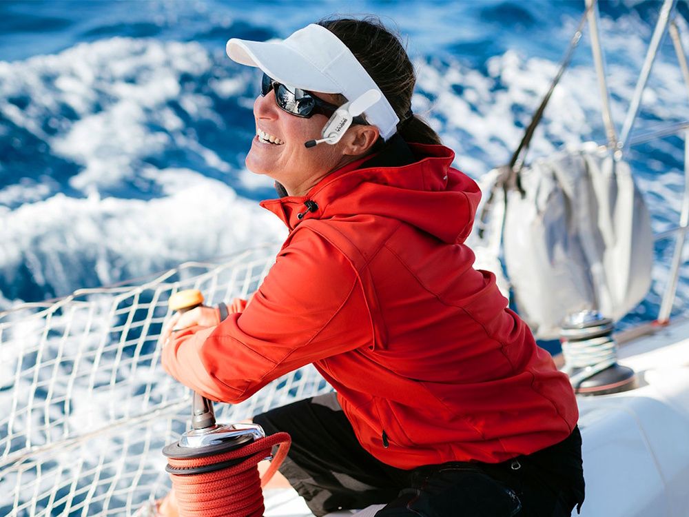 De Sena Nautitalk Crew headset voor communicatie op het water bevestigd aan de pet van een vrouw op een boot op zee
