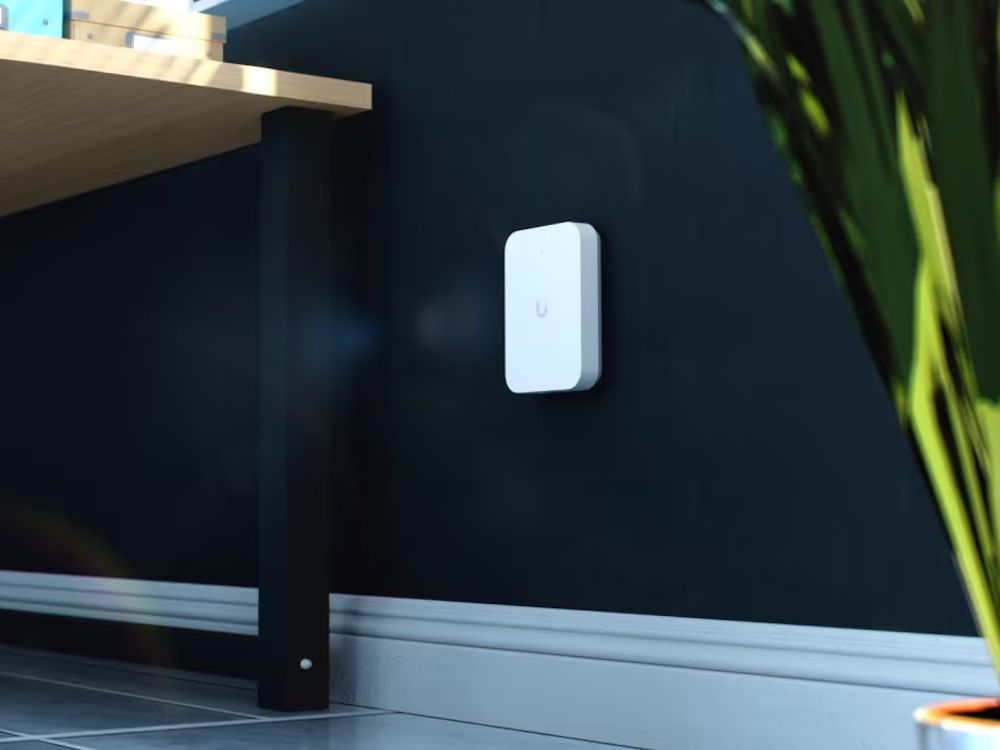 Het Ubiquiti UniFi 7 In-Wall indoor WiFi 7 access point in de muur geplaatst in de buurt van een bureau